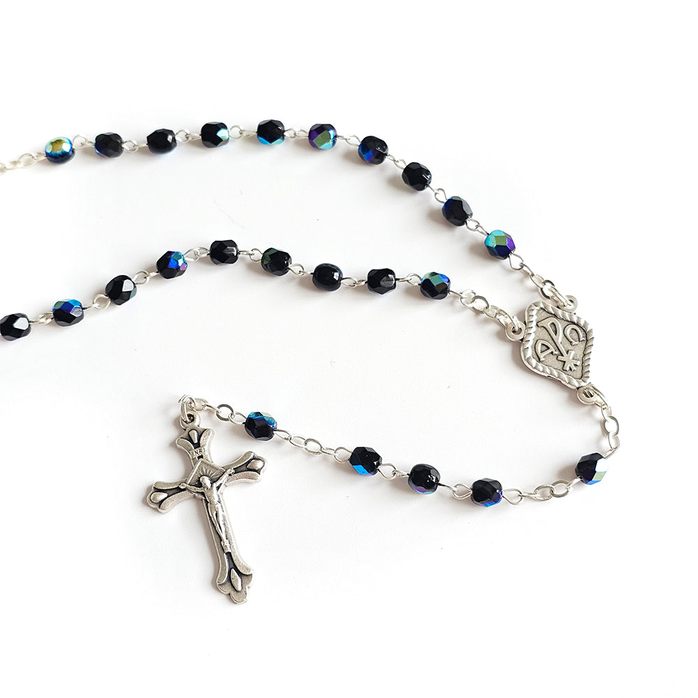 Black Crystal Catholic Rosary with Silver Crucifix and Alpha Omega Centerpiece Rosary with blue beads and silver crucifix on a white background