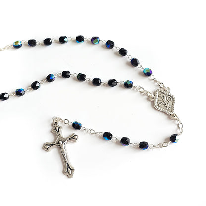 Black Crystal Catholic Rosary with Silver Crucifix and Alpha Omega Centerpiece Rosary with blue beads and silver crucifix on a white background